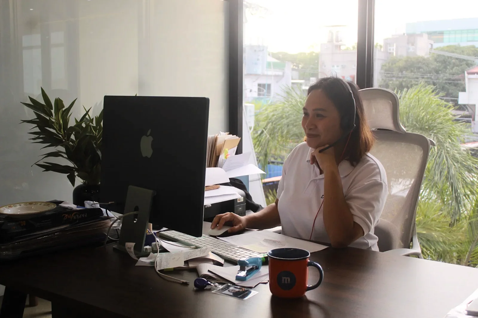 A Desk & VA assistant on a call at her workstation by the window